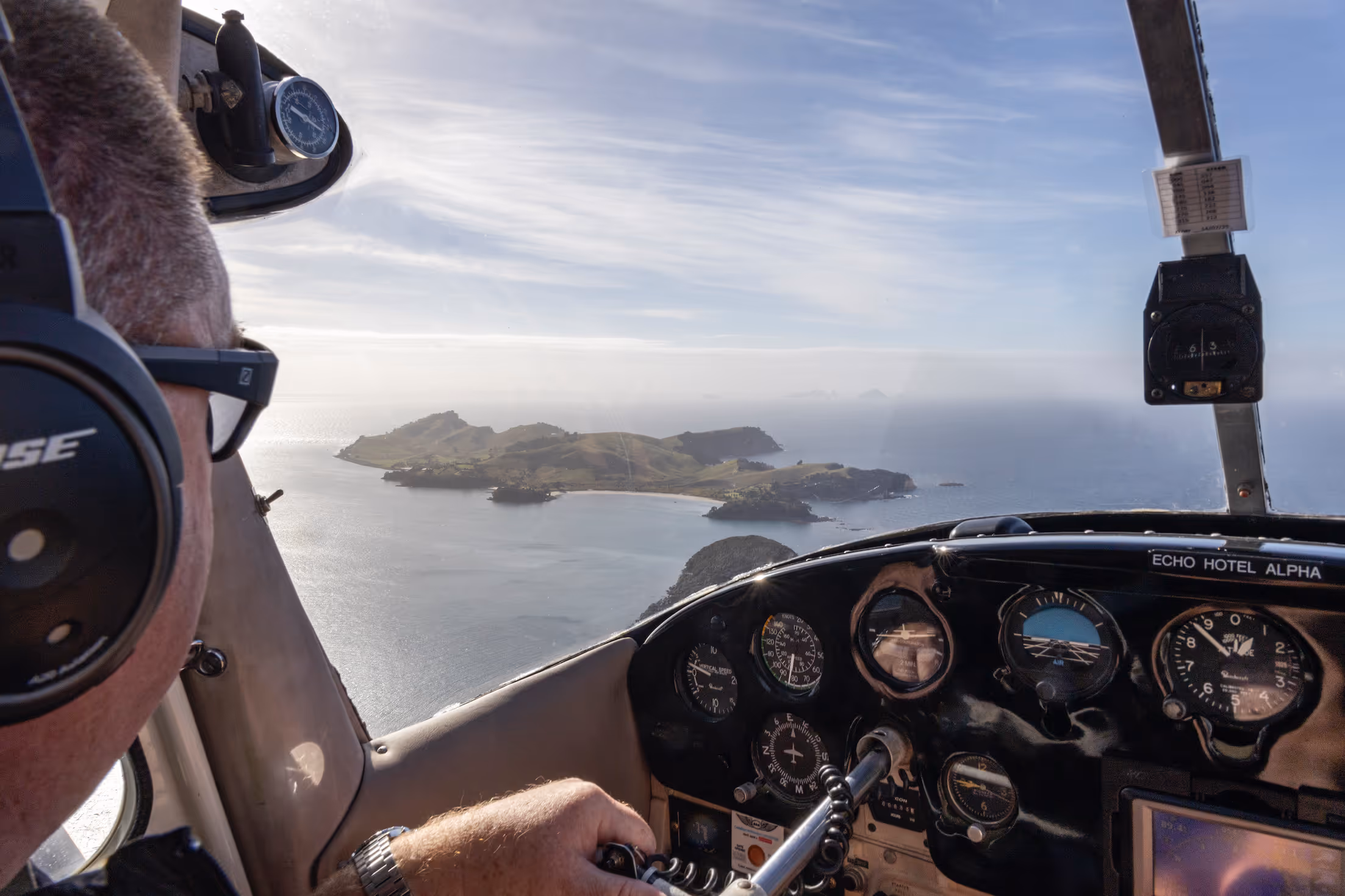 Pilot's perspective from the cockpit, flying over scenic coastal islands in New Zealand. The image showcases the stunning landscape, highlighting the integration of aviation and nature, ideal for Te Kowhai Airpark's aviation community.