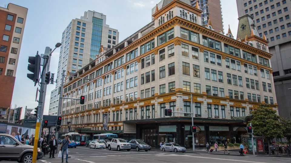 Downing Centre Local & District Court on corner of a busy city intersection with cars and pedestrians.