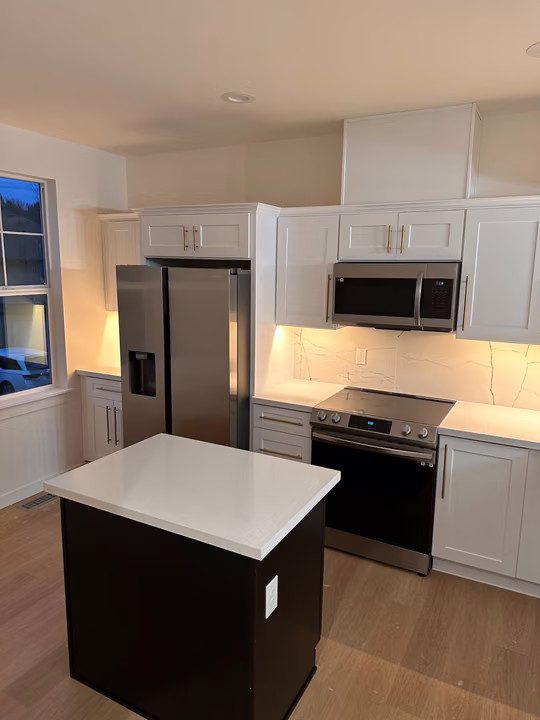 Completed Seattle kitchen with white cabinetry, a dark island and light counters