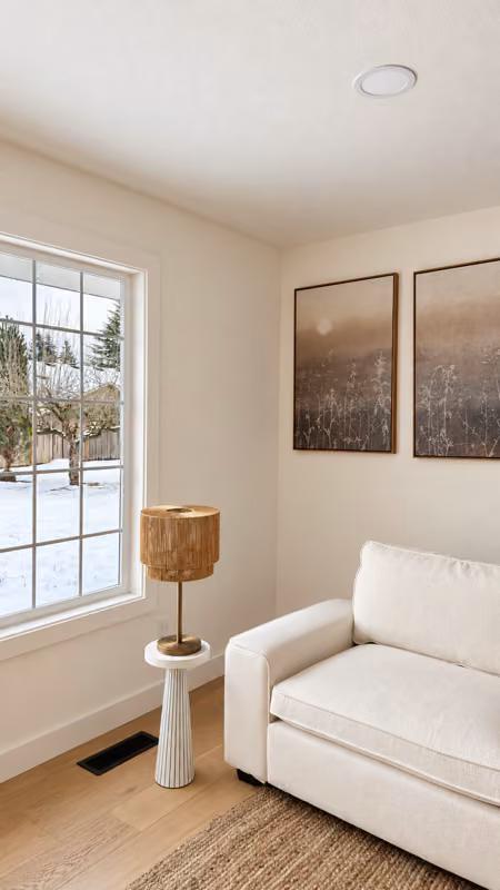 Mukilteo, WA — Finished living-room corner with light flooring, pale wall finishes, and a window-side seating area.