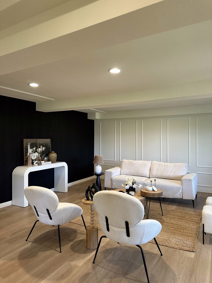 Completed sitting room with contrasting paneled walls, light seating, and wide-plank flooring. Medina, WA.