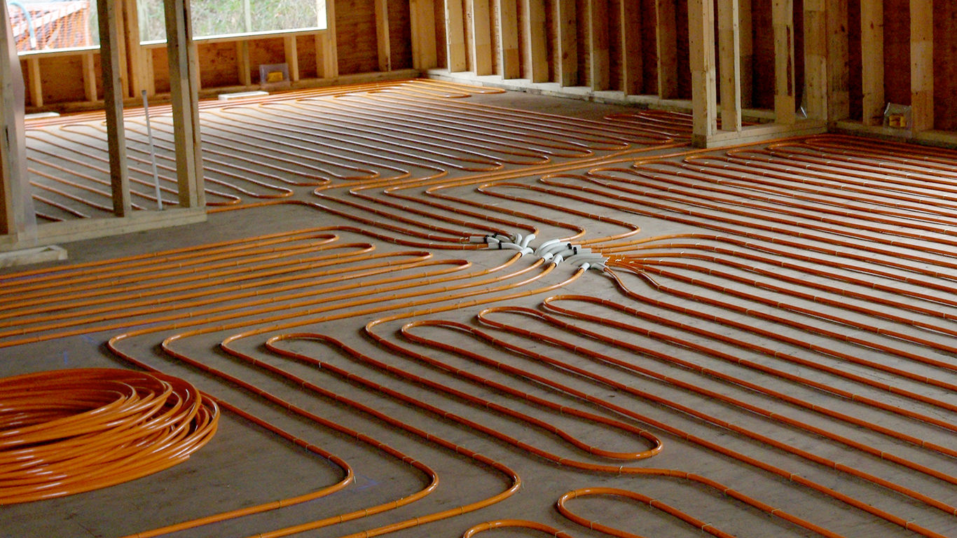 Radiant heating tubes installed across the subfloor of a framed room.