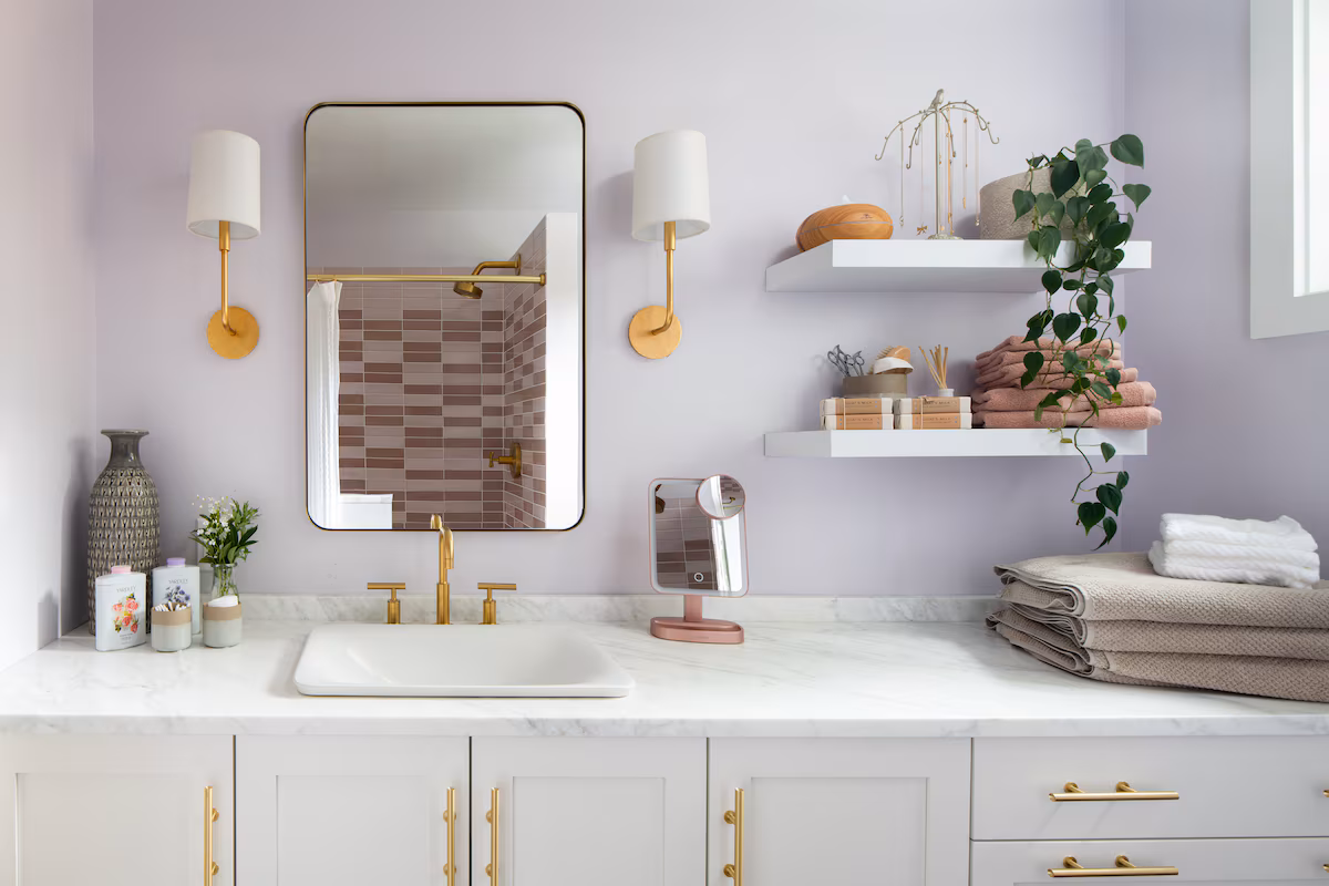 Bathroom vanity with a rectangular mirror, wall sconces, brass hardware, and open display shelves.
