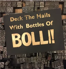 A metal type print saying Deck the Halls With Bottles of Bolli!