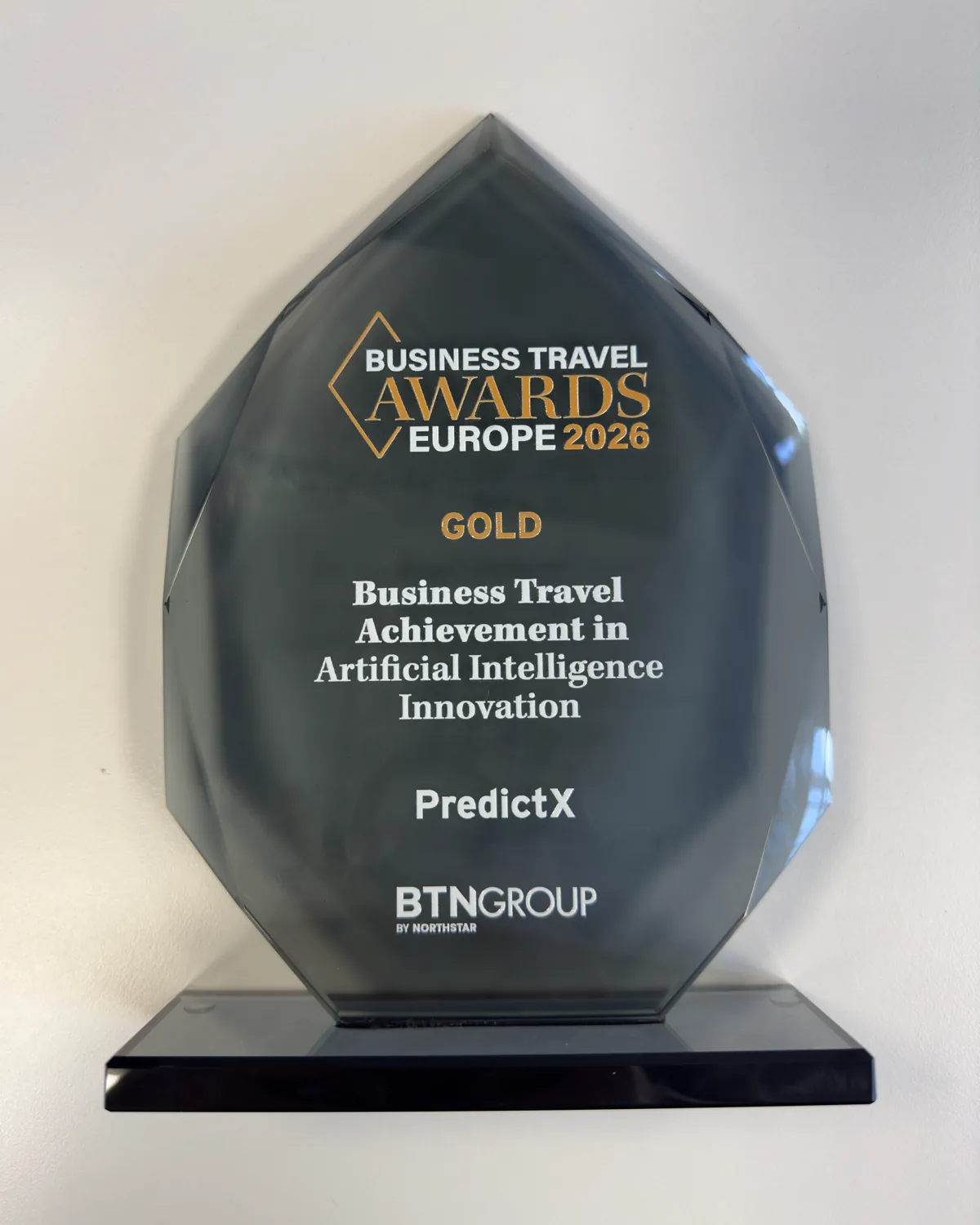 Glass trophy engraved Gold, Business Travel Achievement in Artificial Intelligence Innovation, PredictX, on a grey ground