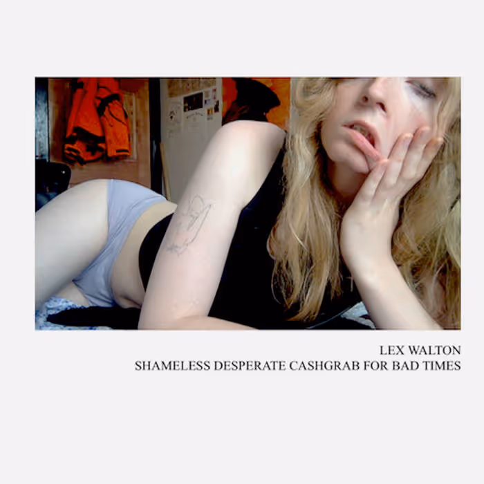 A young womanwith long blonde hair and bangs poses on a bed in a dim bedroom. They wear a black tank top and light gray underwear, resting their face on their hand with a dazed, tired expression. A small line-art tattoo is visible on their upper arm. The room behind them has hanging clothes, posters, and a cluttered wall. Text below reads: “LEX WALTON — SHAMELESS DESPERATE CASHGRAB FOR BAD TIMES.”