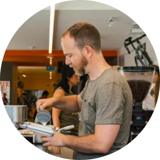 Barista preparing coffee using an espresso machine in a cafe.