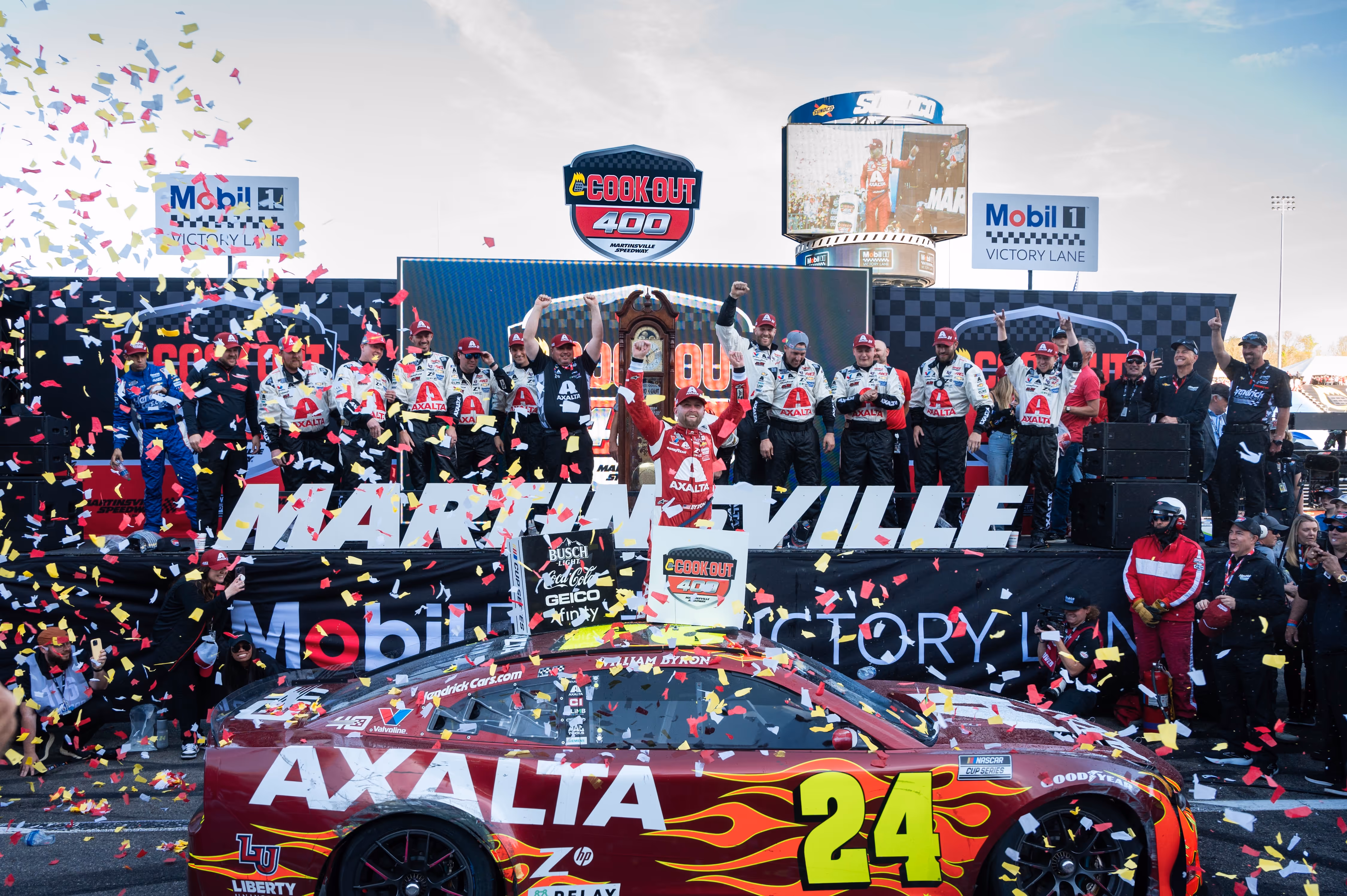 NASCAR driver William Byron celebrating with his team in the Martinsville Speedway victory lane surrounded by confetti and race car number 24.