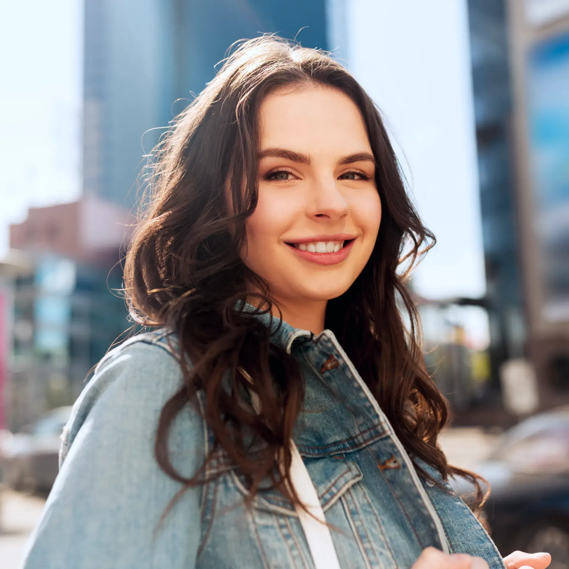 A woman in a jean jacket smiles at the camera.