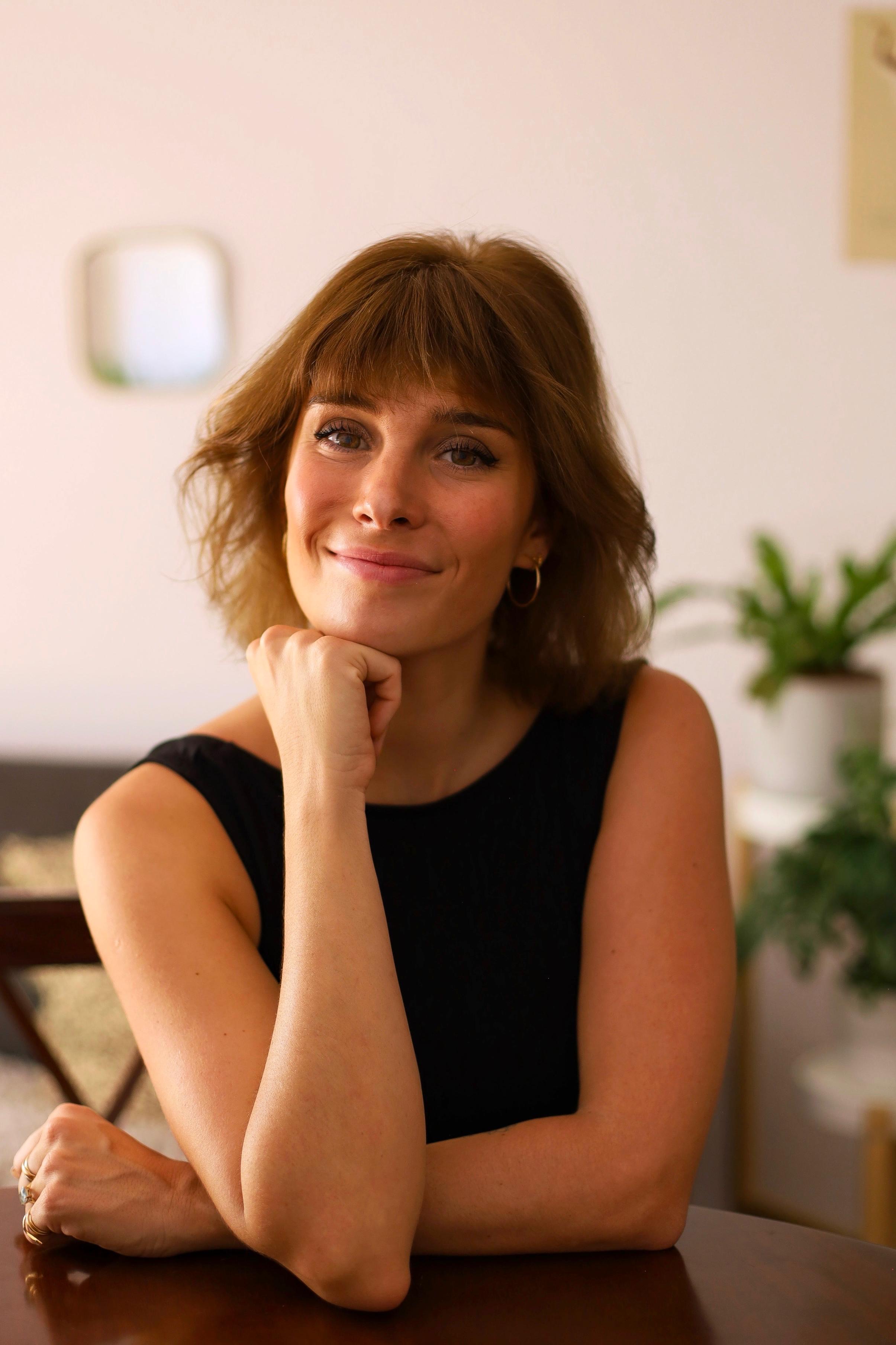 A picture of Rosalie, a French tutor smiling at camera with her chin on her fist.