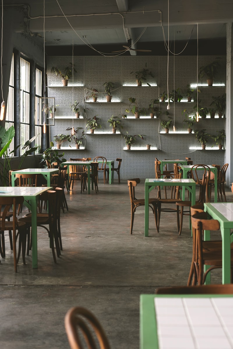 Empty restaurant interior with green tables and chairs in soft daylight