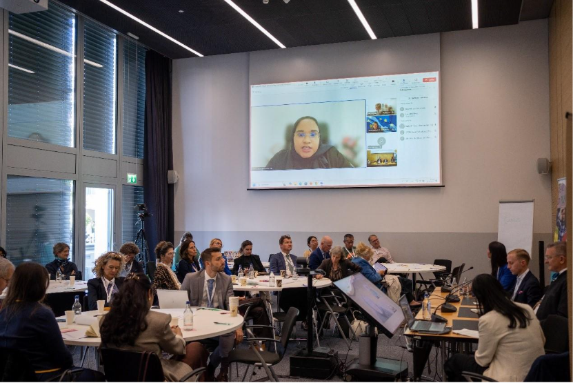 A group of people sitting at tables in a room with a projector screenAI-generated content may be incorrect.