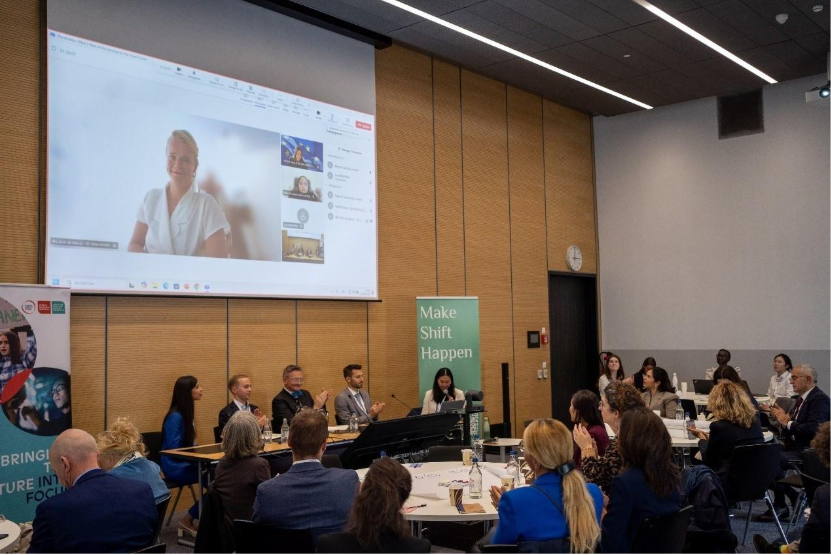 A group of people sitting at tables in front of a projector screenAI-generated content may be incorrect.