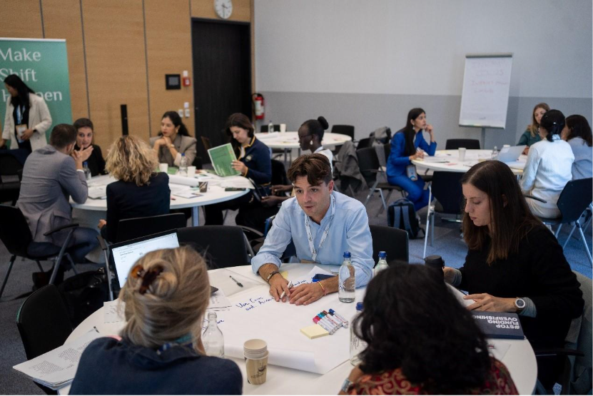 A group of people sitting around tablesAI-generated content may be incorrect.