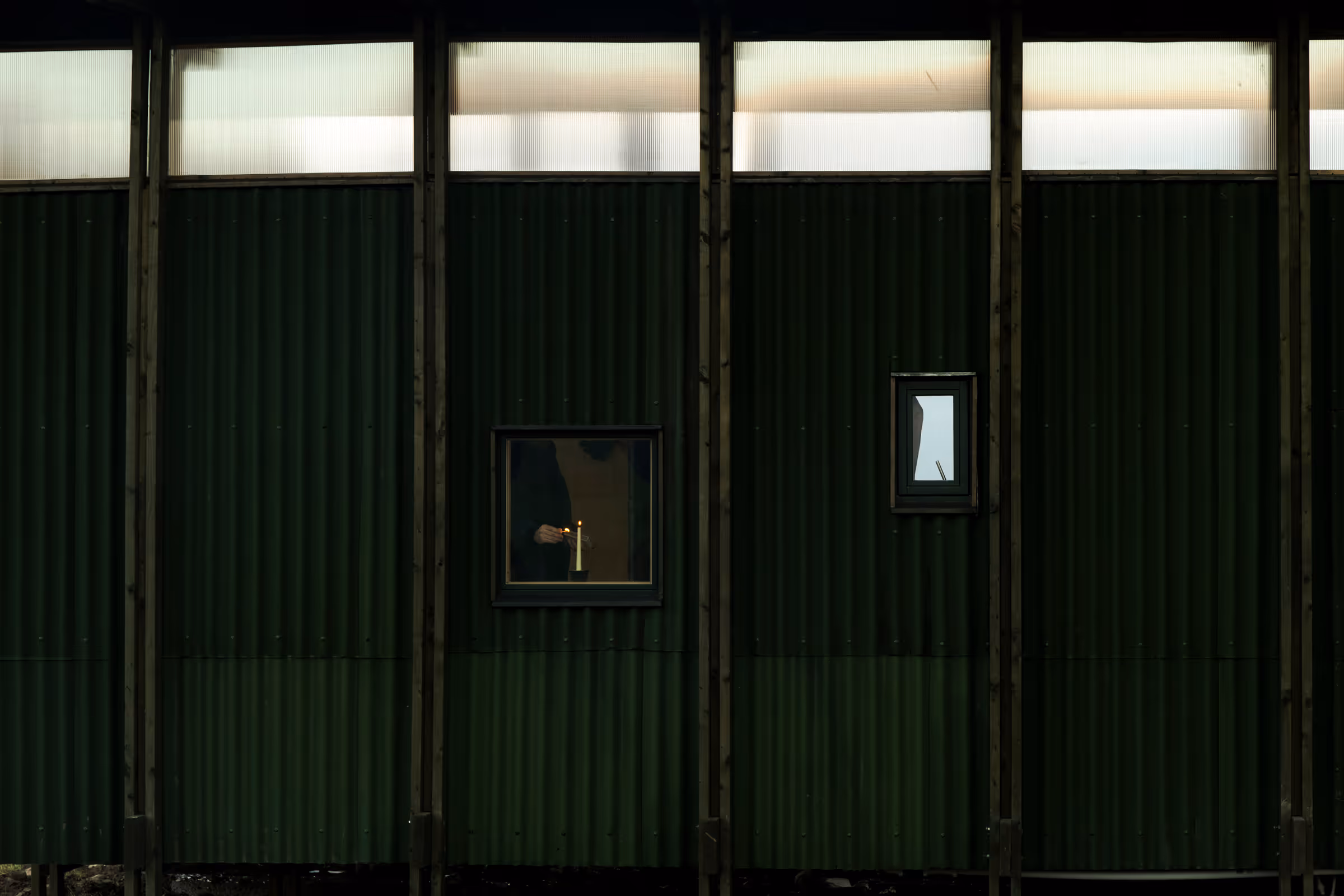 Side of cabin under the hills with candle being lit