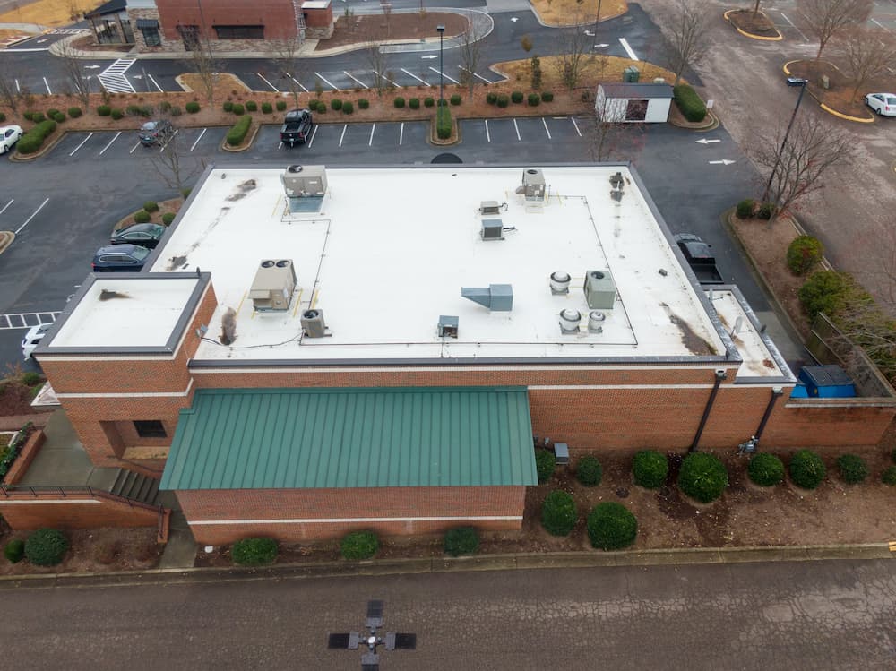 Aerial view of a large commercial building with multiple rooftop HVAC units, emphasizing the essential need for professional, scheduled maintenance and repair for commercial HVAC services.