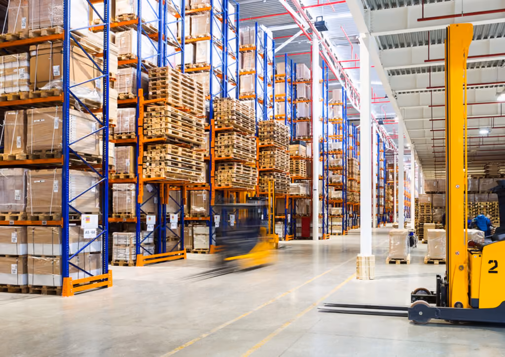 Warehouse aisle with racked pallets and a forklift moving packaging inventory