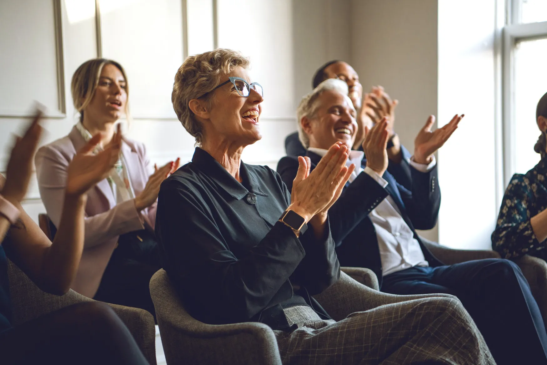 Happy audience of pre-retirees clapping at a high-impact AcquireUp seminar