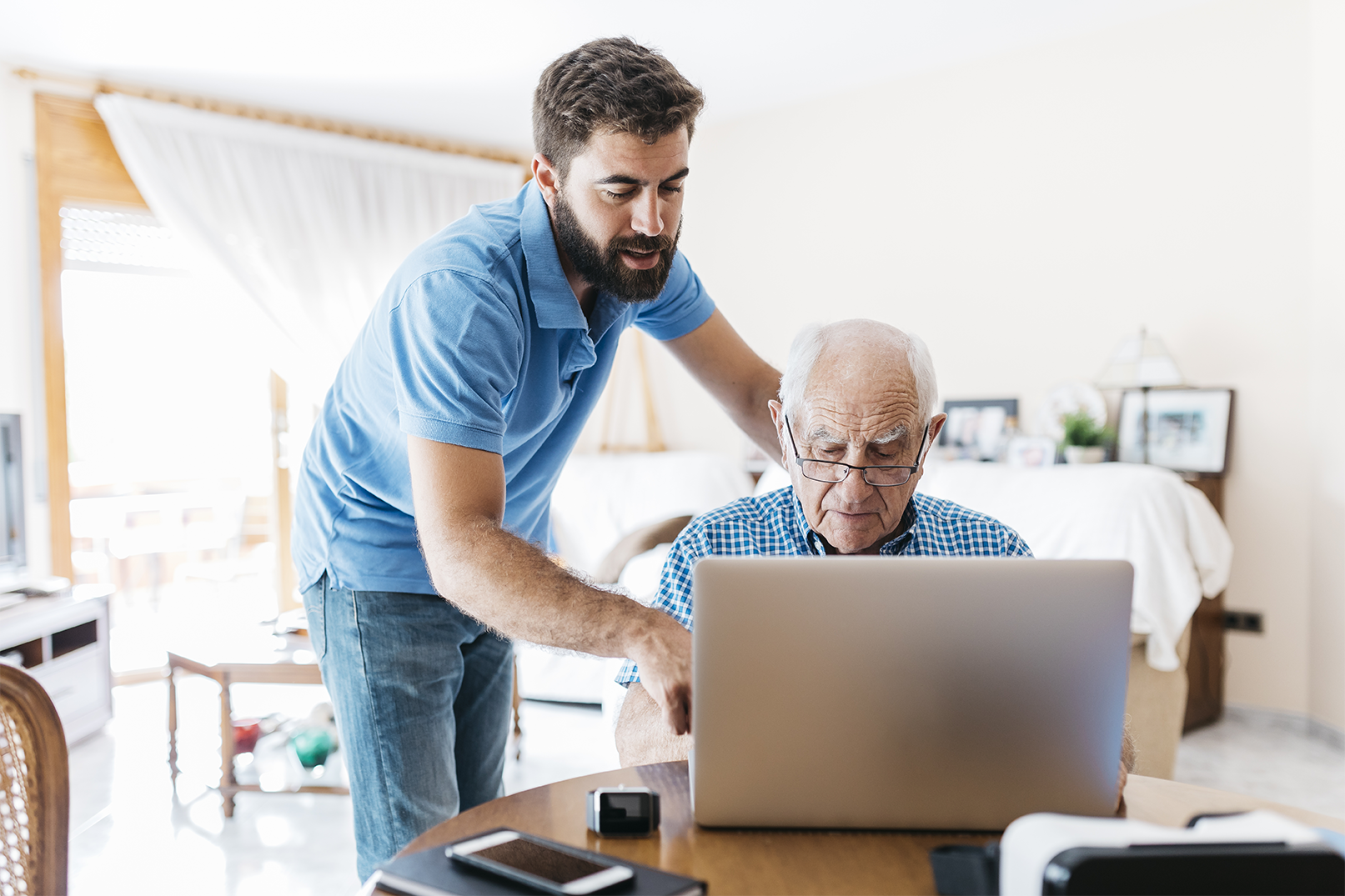 A man helps his elderly father on the laptop in an office
