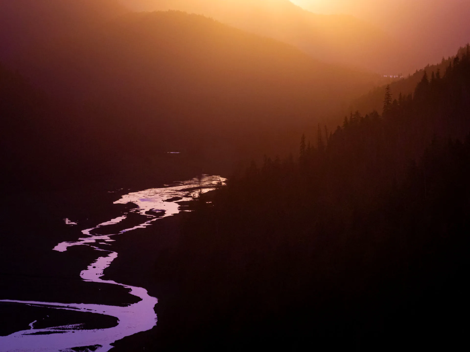 Winding river reflecting purple and orange hues at sunset in Sitka, Alaska.