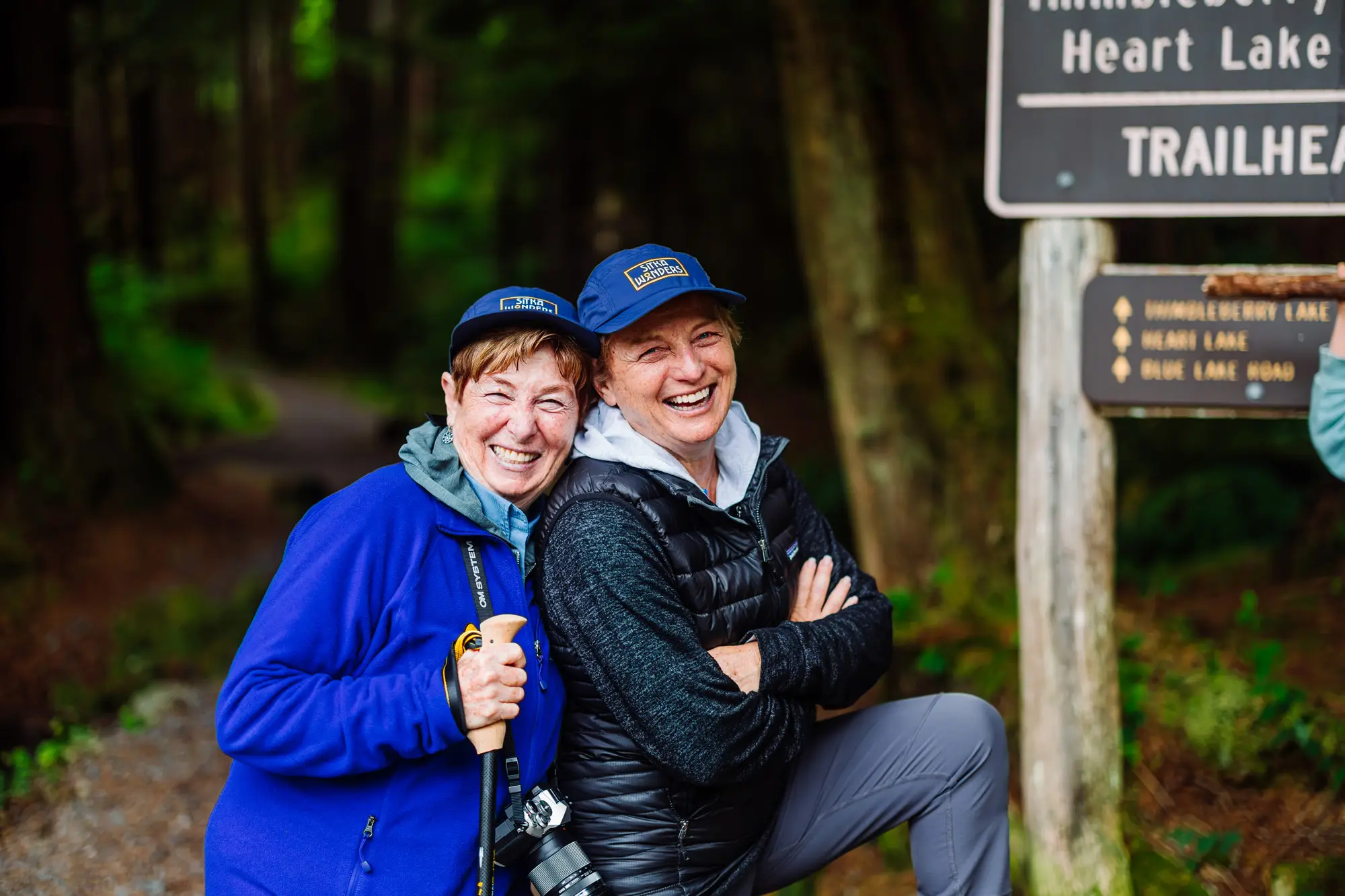 Two guests laughing at a trailhead in the rainforest near Sitka