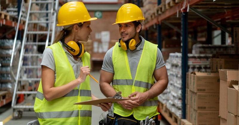 a warehouse worker's holding a report and discussing it with each other