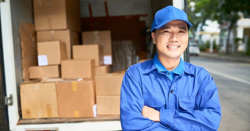 a delivery person crossing his arms for a pose and smiling