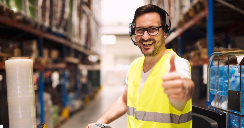 a warehouse worker smiling and giving a thumbs-up