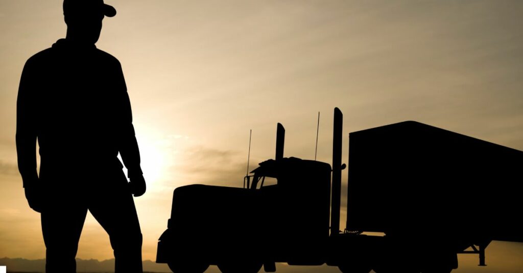 a person standing next to a large truck at sunset