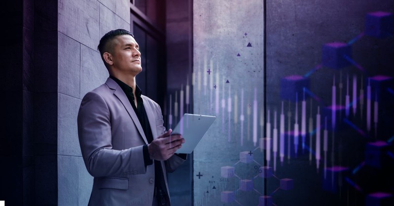 a man in a suit holding a tablet and looking at digital charts and graphs