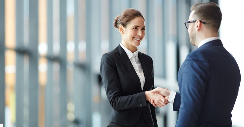 a man and a woman in business attire shaking hands