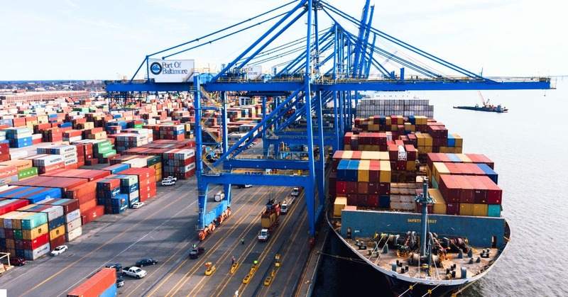 a large cargo ship is docked, and the containers are being loaded or unloaded