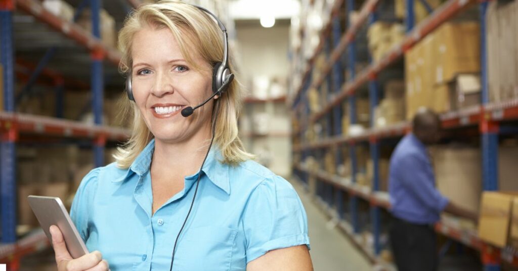 a woman wearing a headset and holding a tablet in a warehous