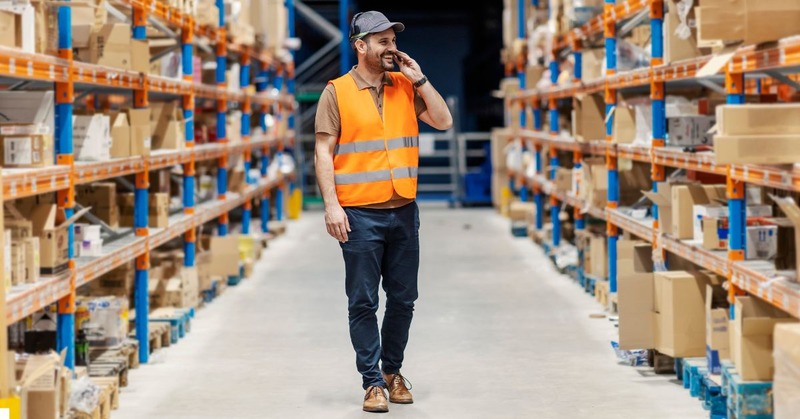 a warehouse worker smiling and talking on the headset