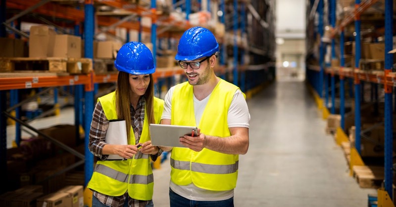 two warehouse employees checking the current status of their tasks via an ipad