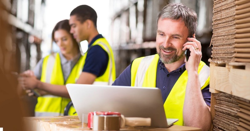 a warehouse worker looking at his laptop while taking a call