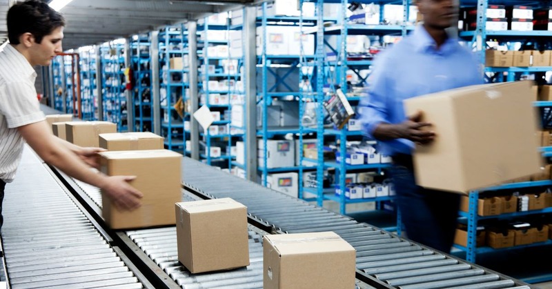 a warehouse worker's picking boxes up through a conveyor with a bunch of boxes