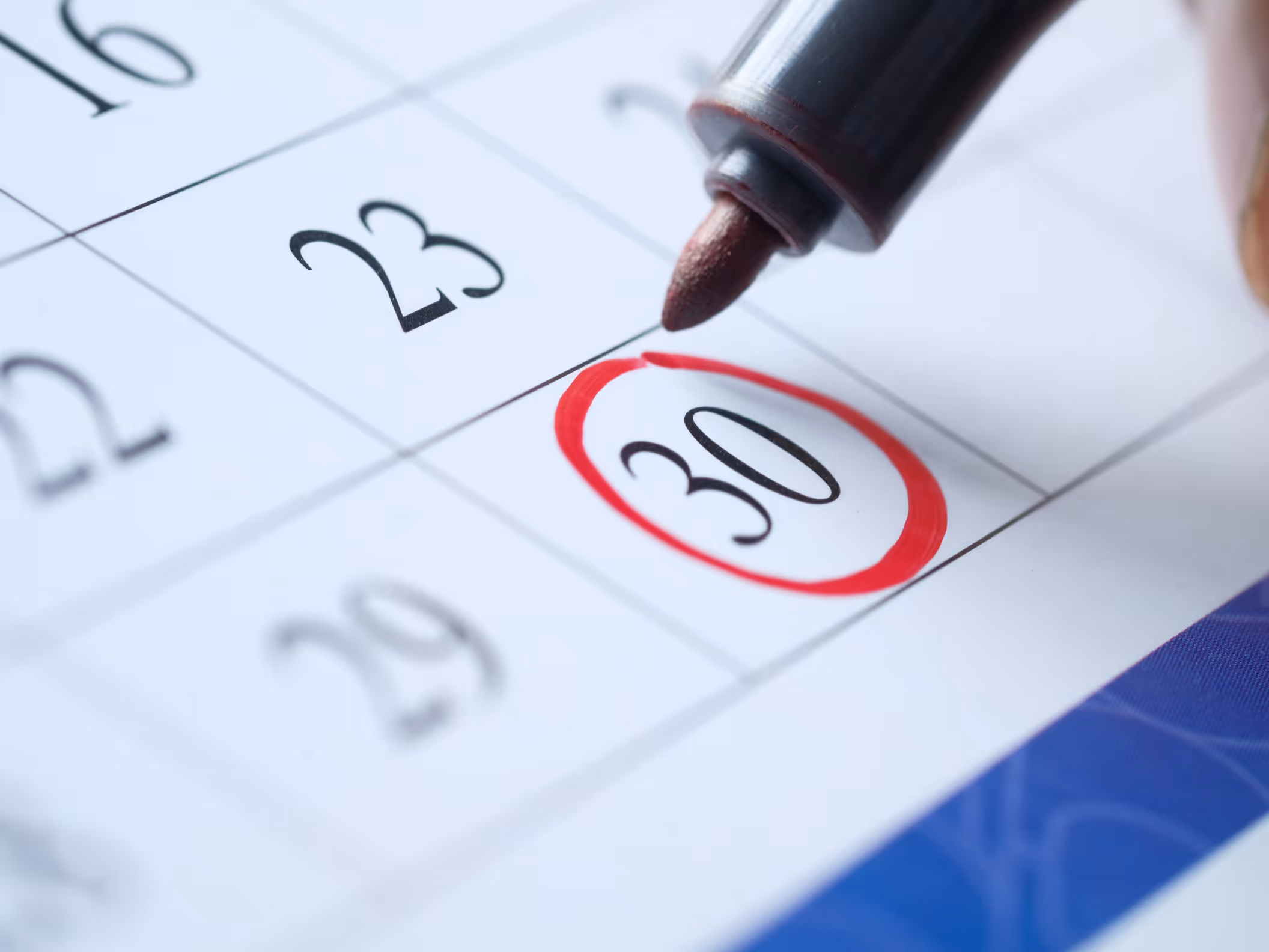 Close up of a pen with red ink circling the 30th on a calendar.