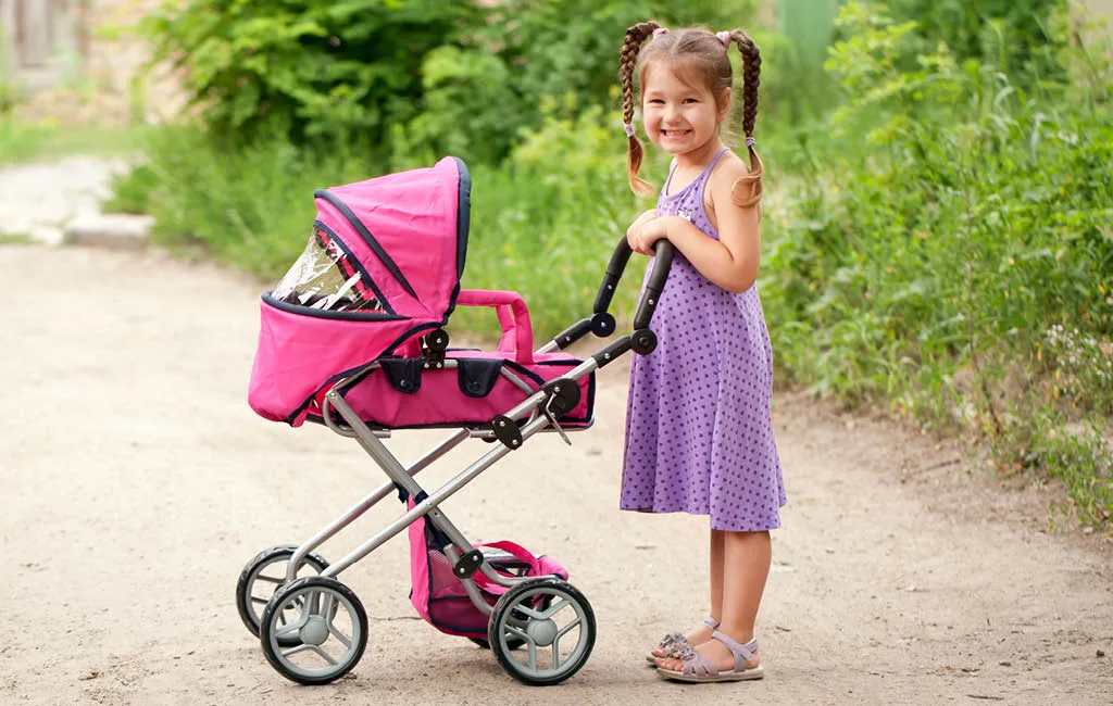 Little girl pushing a toy stroller.