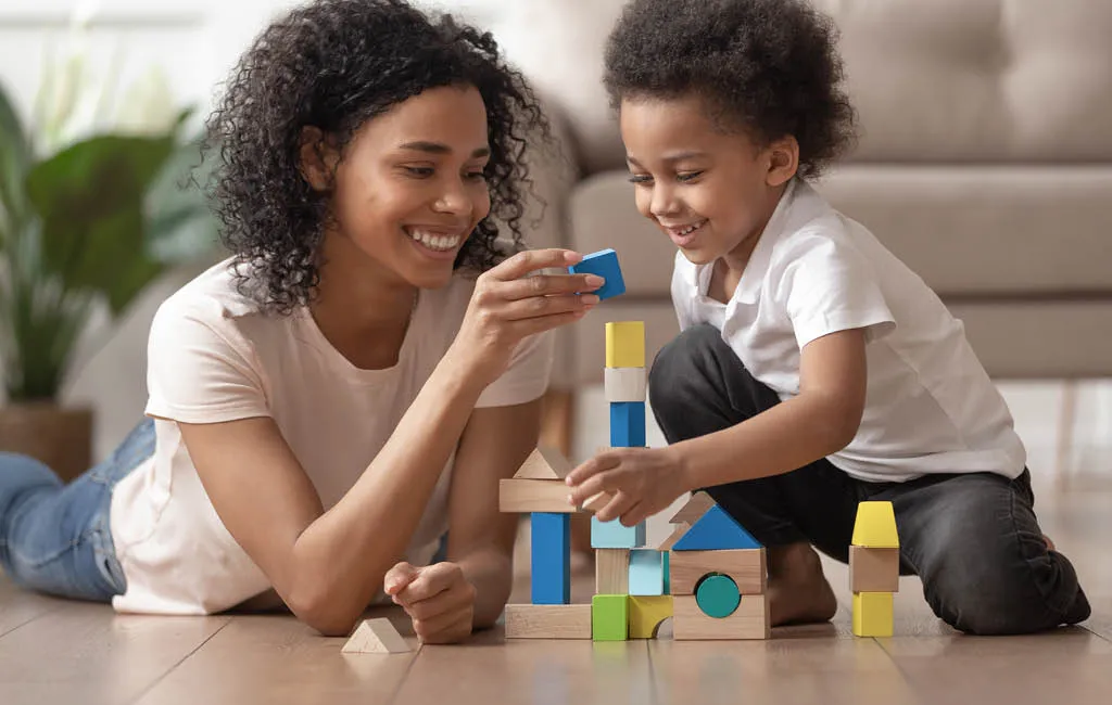 Mother and son build together with wooden blocks.