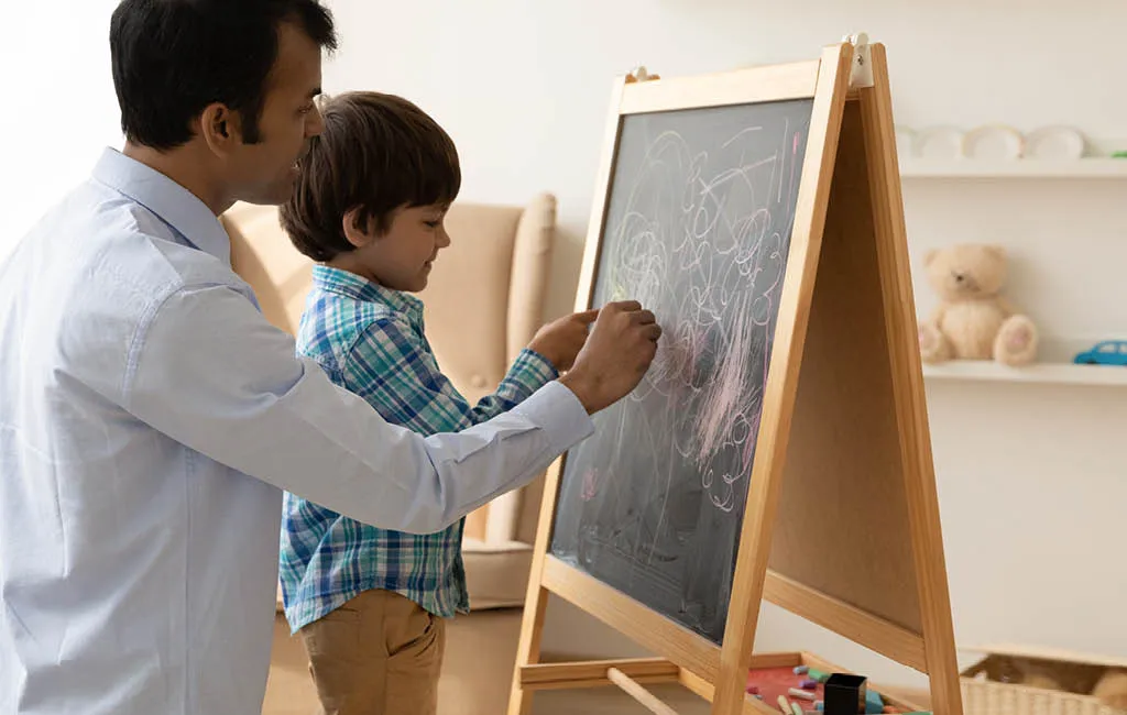 Dad and son drawing on a chalkboard.