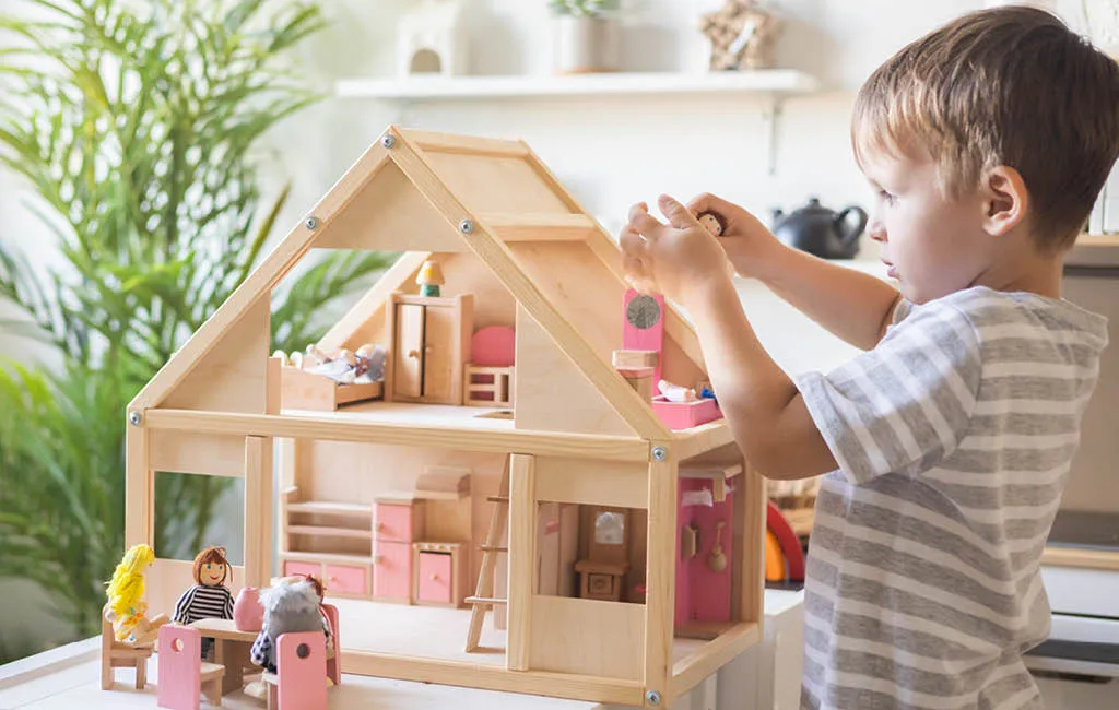 Child playing with a wooden dollhouse.