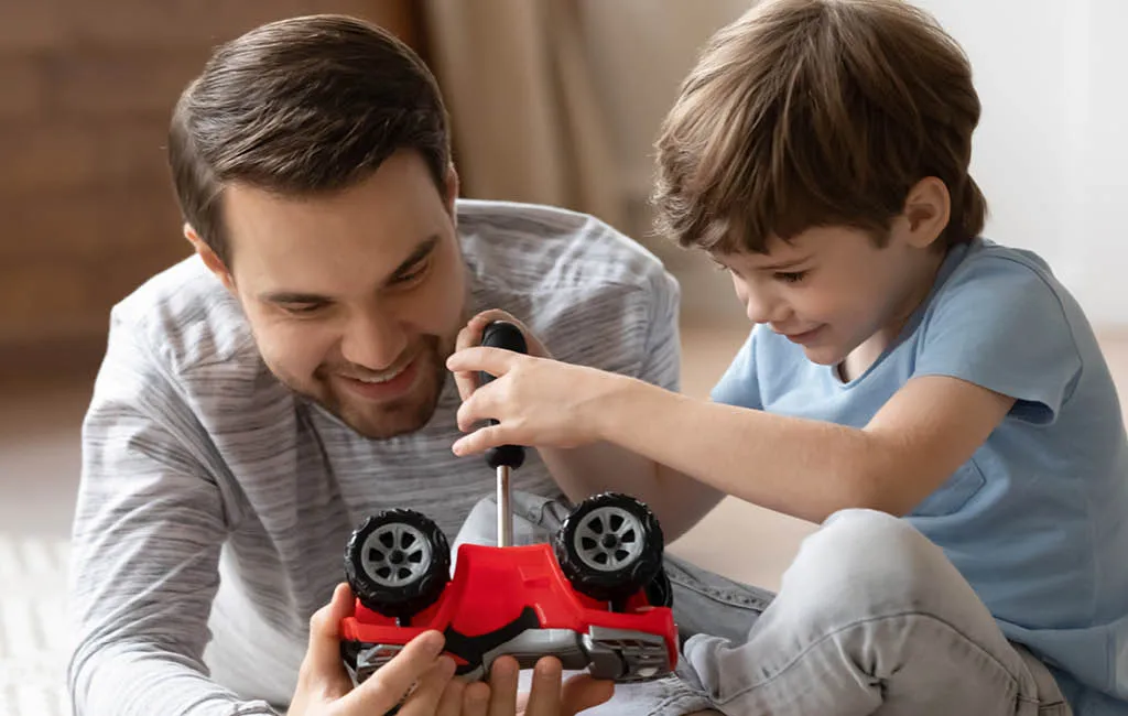 A boy with a screwdriver together with his father.