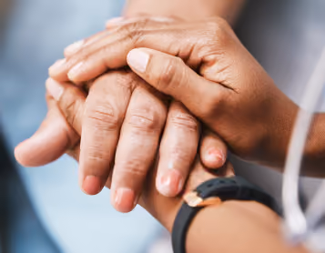Young caregiver's hands gently holding an elderly person's hand