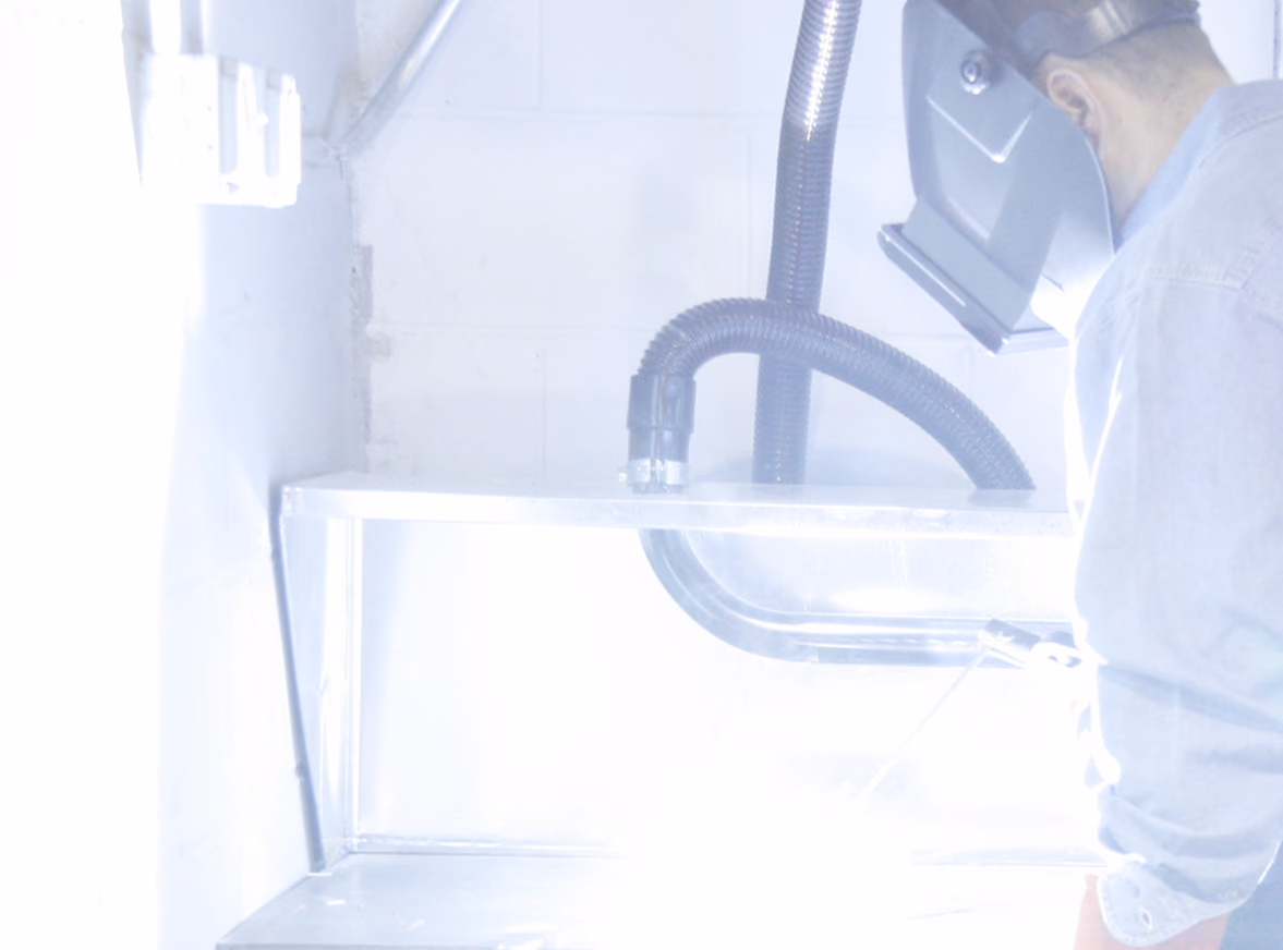 Welder in a protective hood welds sheet metal in a workshop