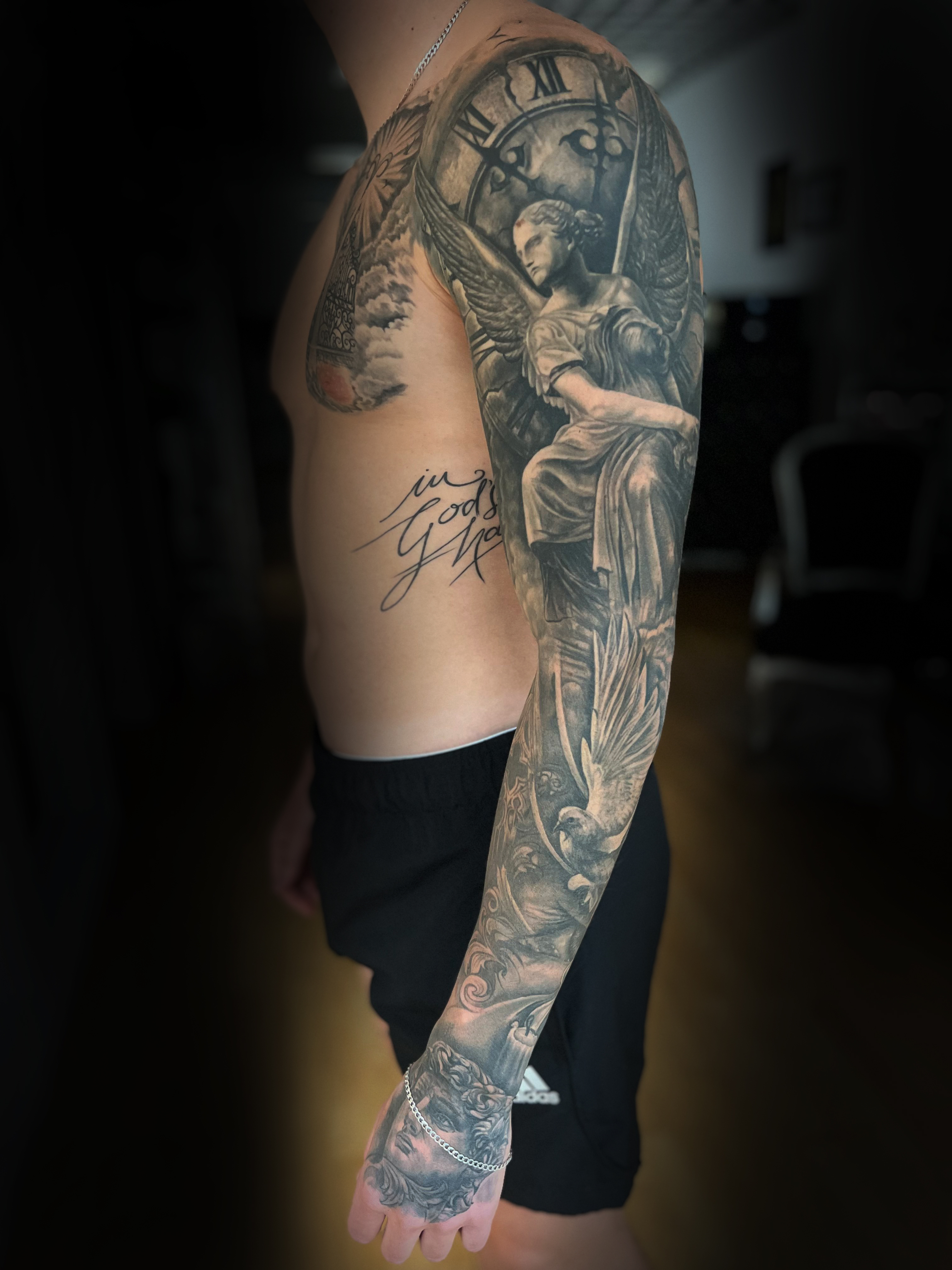 Nahaufnahme der Hand eines Tattoo Artists mit Sleeve Arm und Brust eines Black & Grey Tattoos in München.