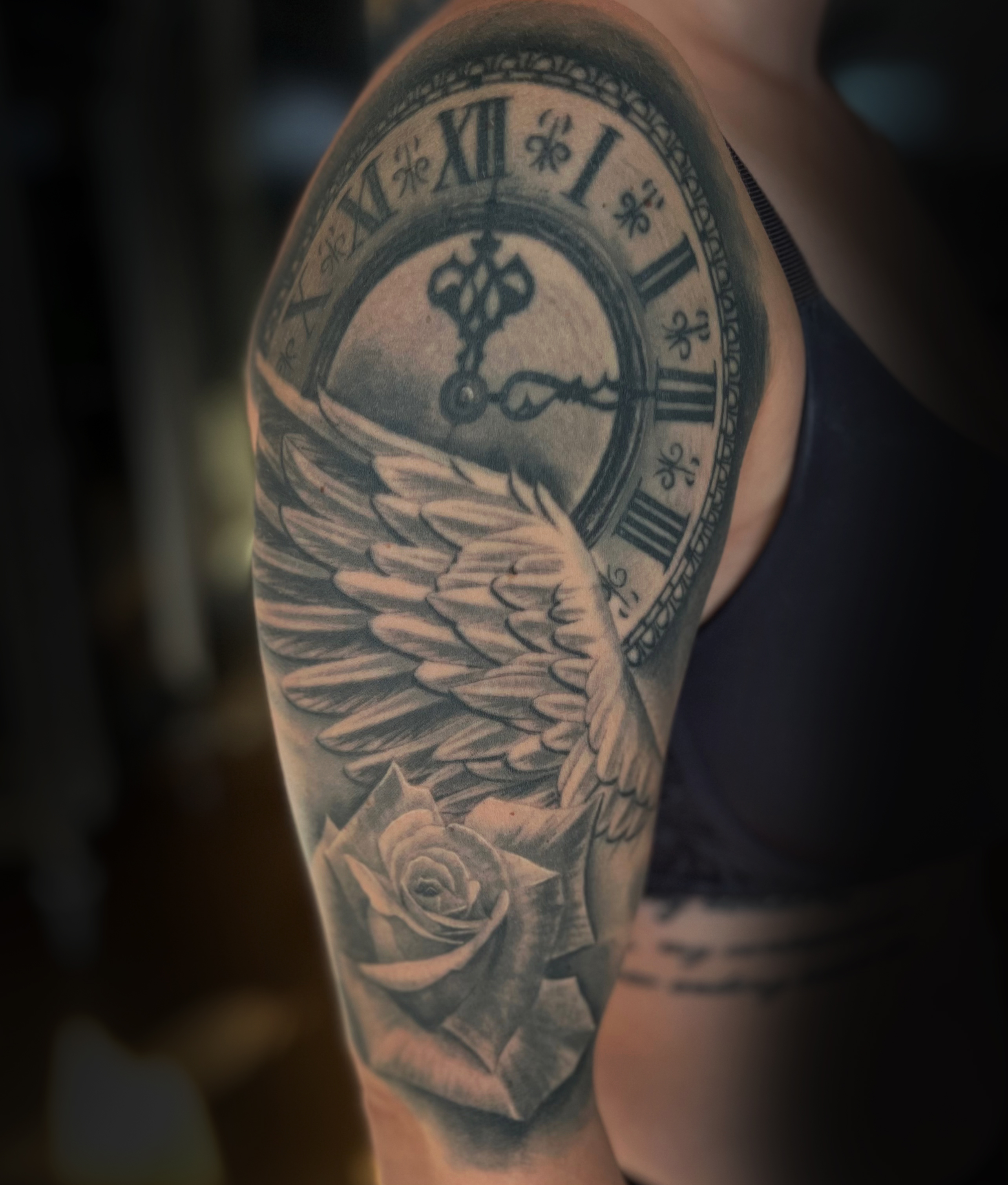 Realistische Licht- und Schattendetails eines Black & Grey Tattoos Flügel, Uhr und Rose im Avantgarde Studio München.