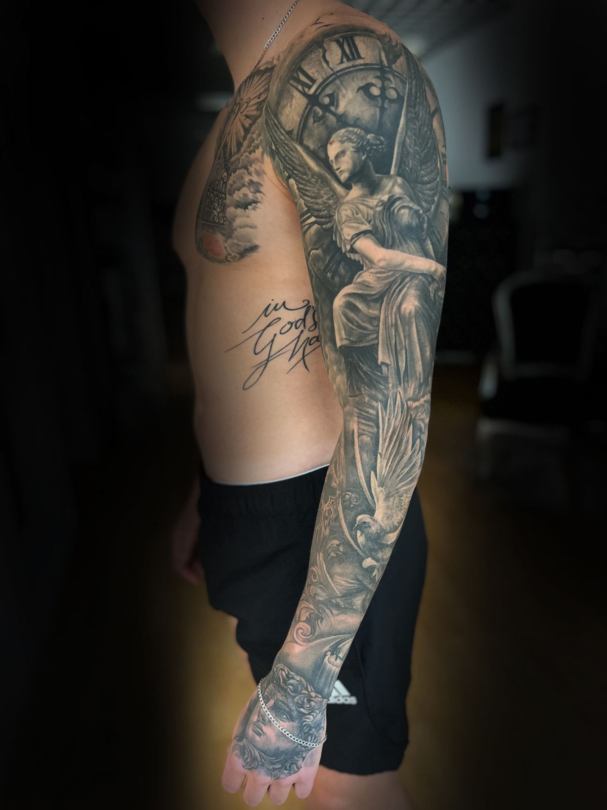 Nahaufnahme der Hand eines Tattoo Artists mit Sleeve Arm und Brust eines Black & Grey Tattoos in München.