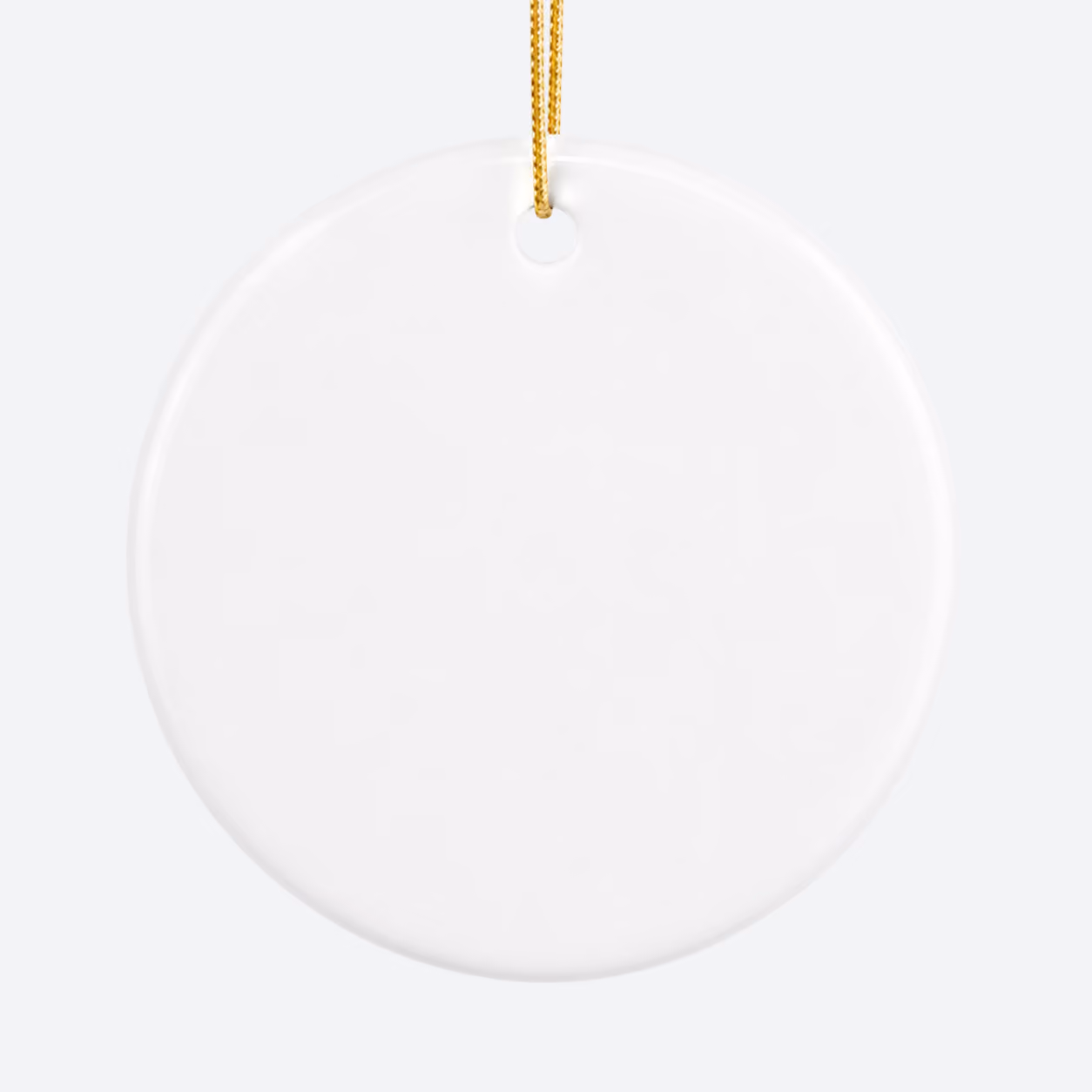Plain white round ceramic ornament hanging by a gold string on a light gray background.