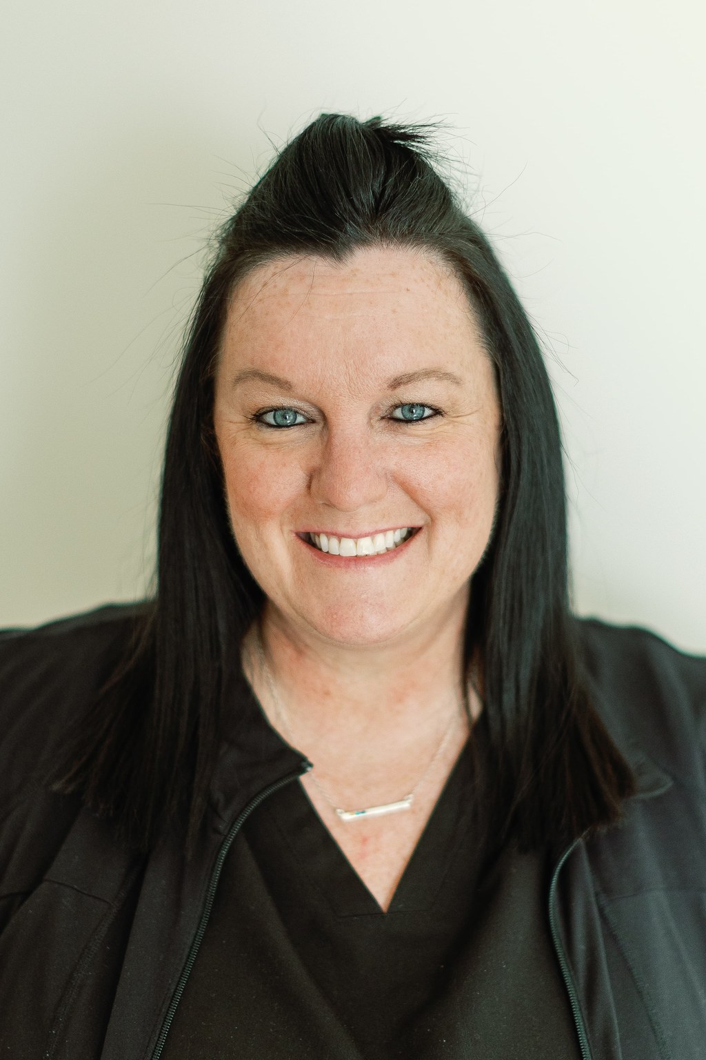 Nicki, Treatment Coordinator at Peterson Orthodontics, smiling in a black scrub top.